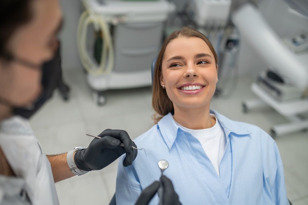 Dentist examining patient teeth using mouth mirror and dental probe in clinic