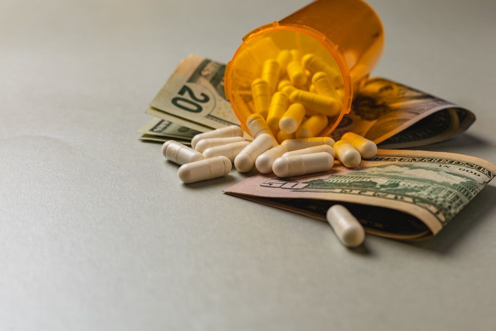 Pills are scattered on a table next to folded cash