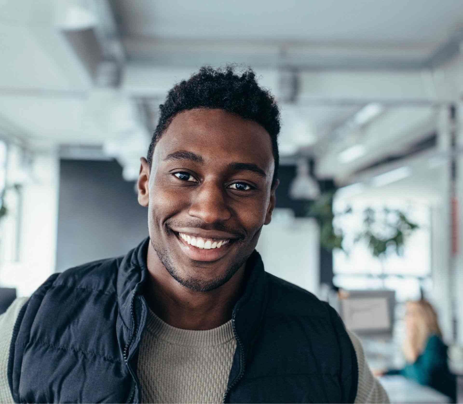 A man wearing a black vest is smiling for the camera