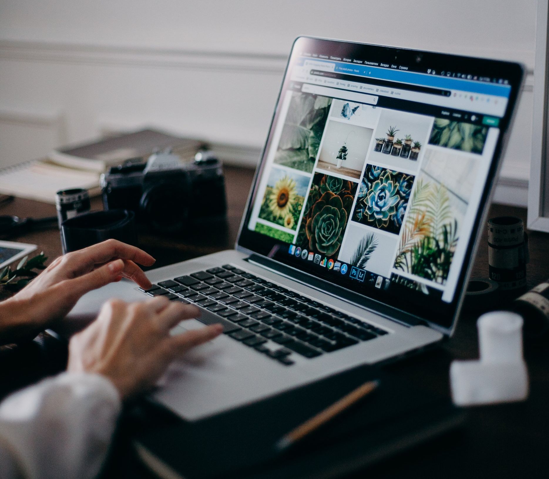 A person is typing on a laptop computer with pictures on the screen.