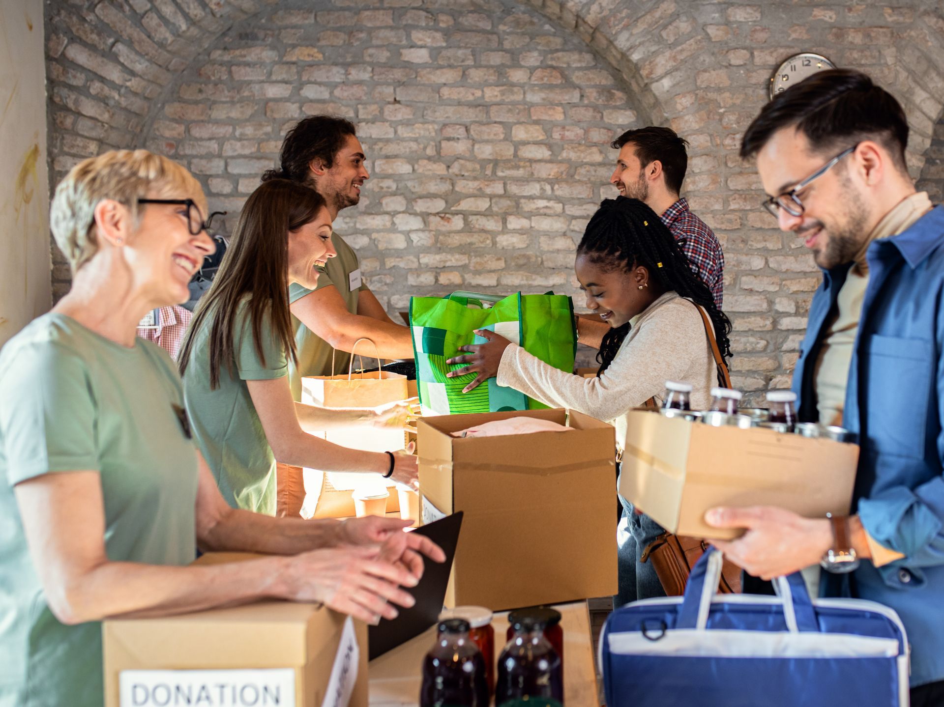 Volunteers packing donations at a community center. Boxes and bags are filled with food and supplies.