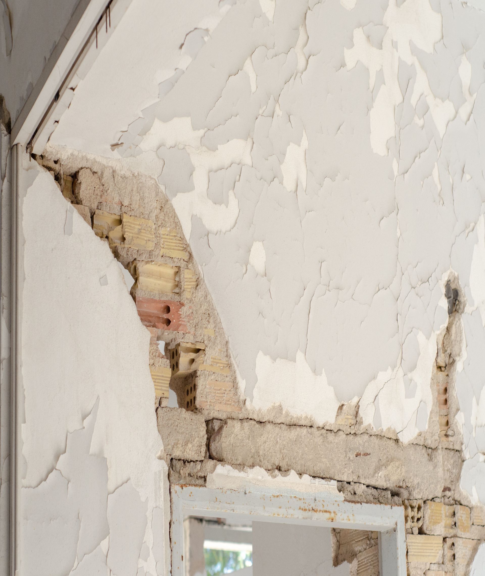 A wall with a hole in it and a window in it.