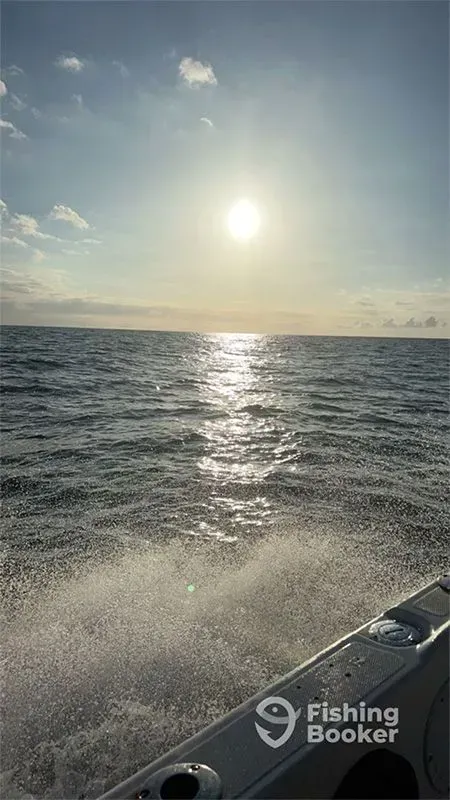 Sunset over choppy ocean from a fishing boat, with sparkling water and the boat’s bow in the foreground