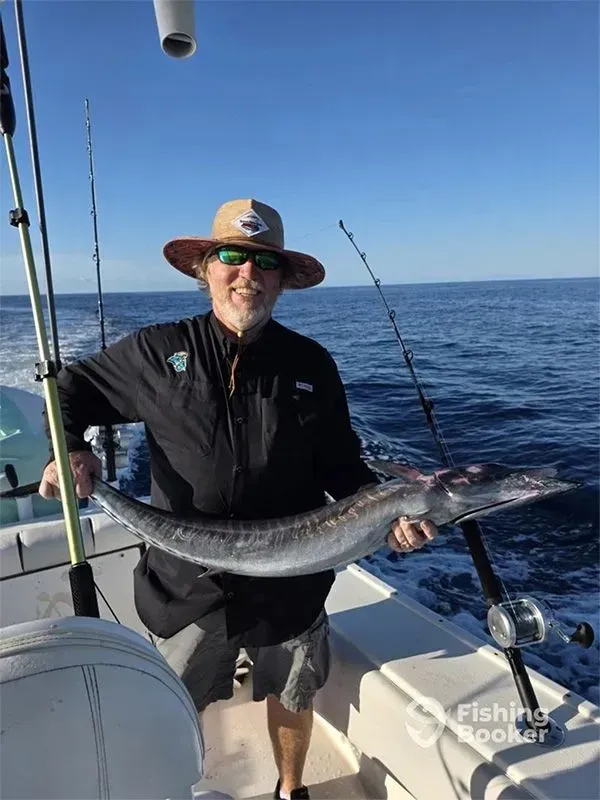 Angler on a boat holding a large fish on a sunny ocean trip