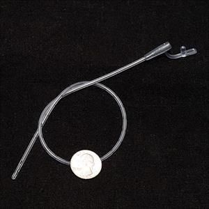 A clear catheter with a penny on it is sitting on a black surface.