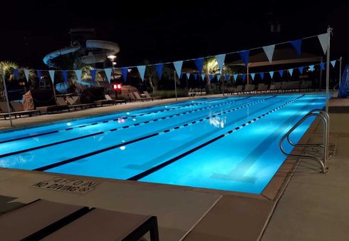A large swimming pool is lit up at night.