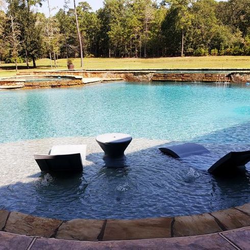 A large swimming pool with a few chairs in it