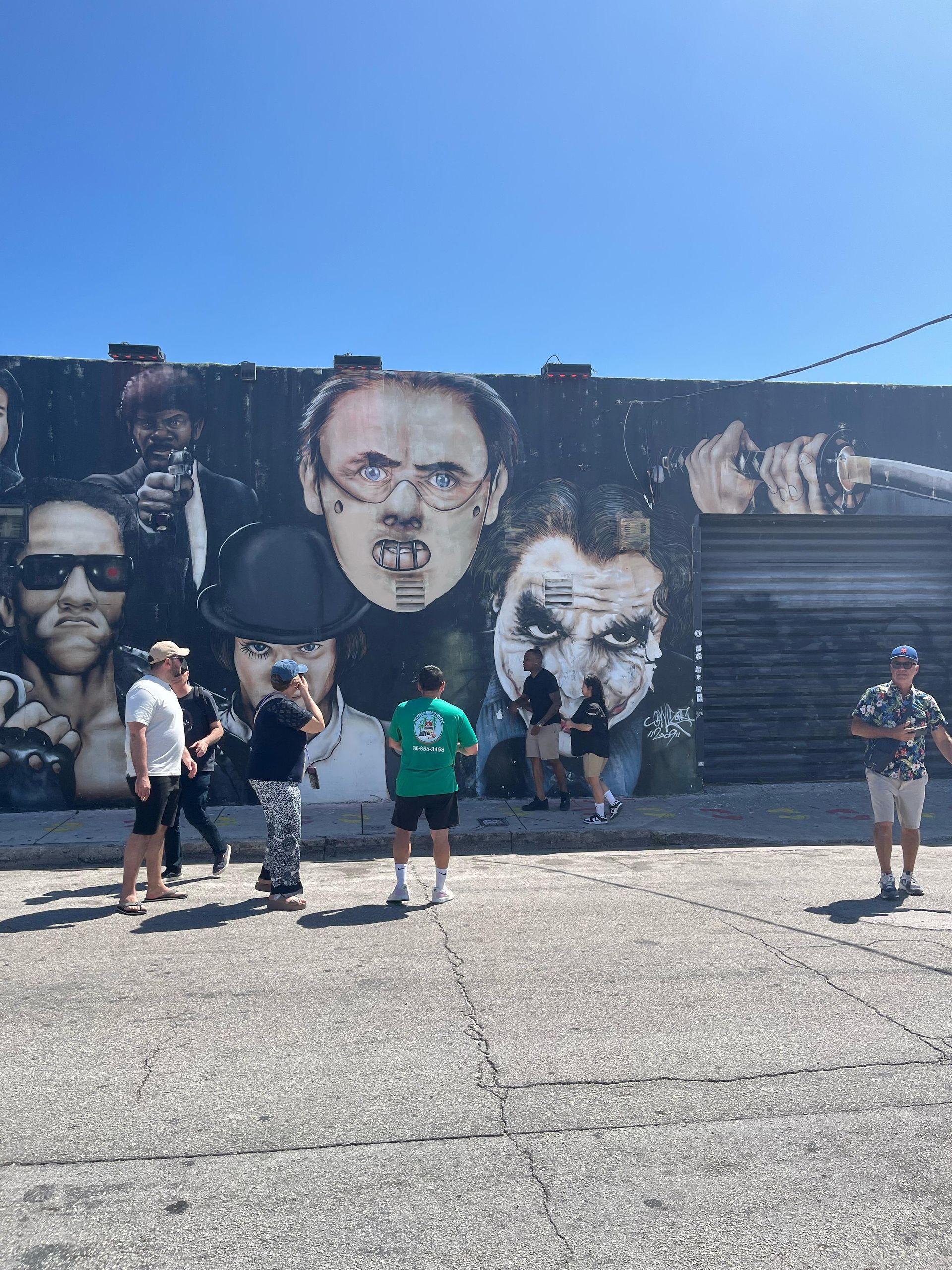 Tour guide in green with passengers in wynwood walls gangster mural part of the top City bus tour in Miami