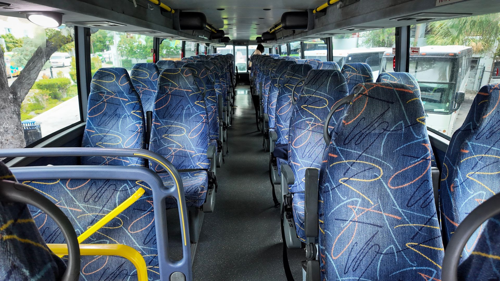 Interior view of a Miami to Key West tour bus with blue patterned seats and wide windows
