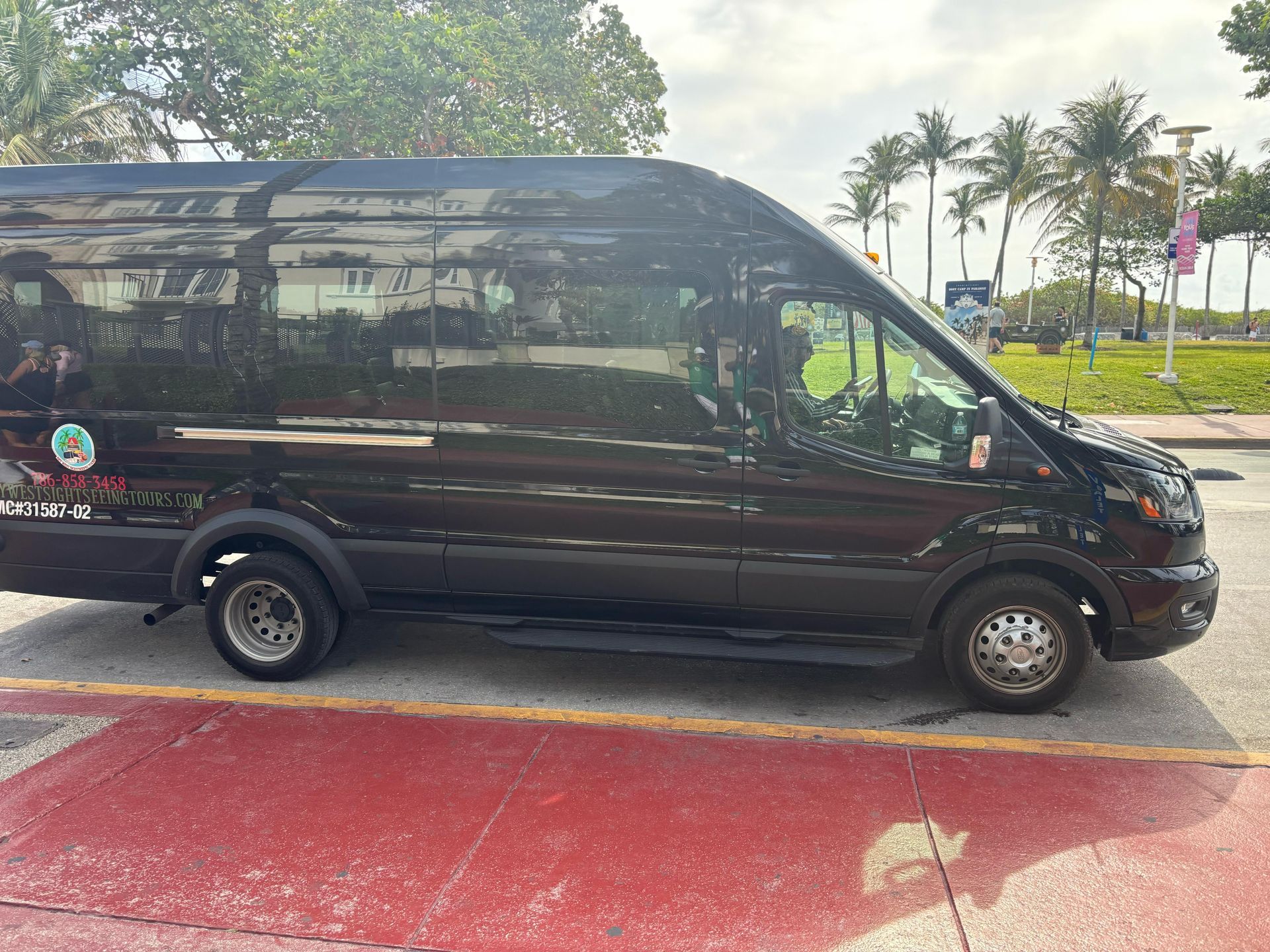 Black Miami tour bus parked on Ocean Drive for small group sightseeing tour in South Beach
