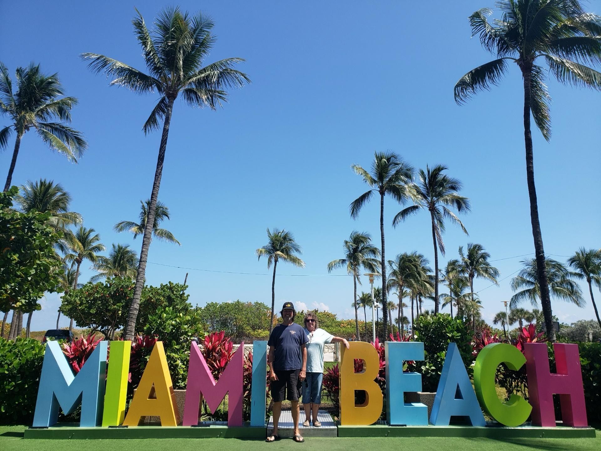 Guests posing at the colorful Miami Beach sign during the South Beach walking tour on the small group Miami sightseeing tour

