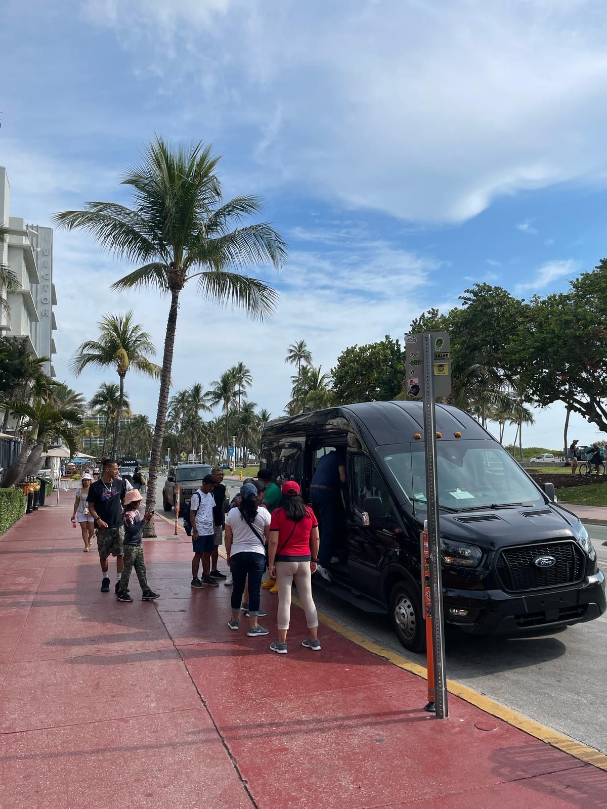 Small group Miami sightseeing tour guests boarding black transit bus on Ocean Drive in South Beach
