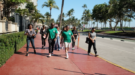 Miami Bus Tours guests walking with guides near the Versace Mansion on Ocean Drive.