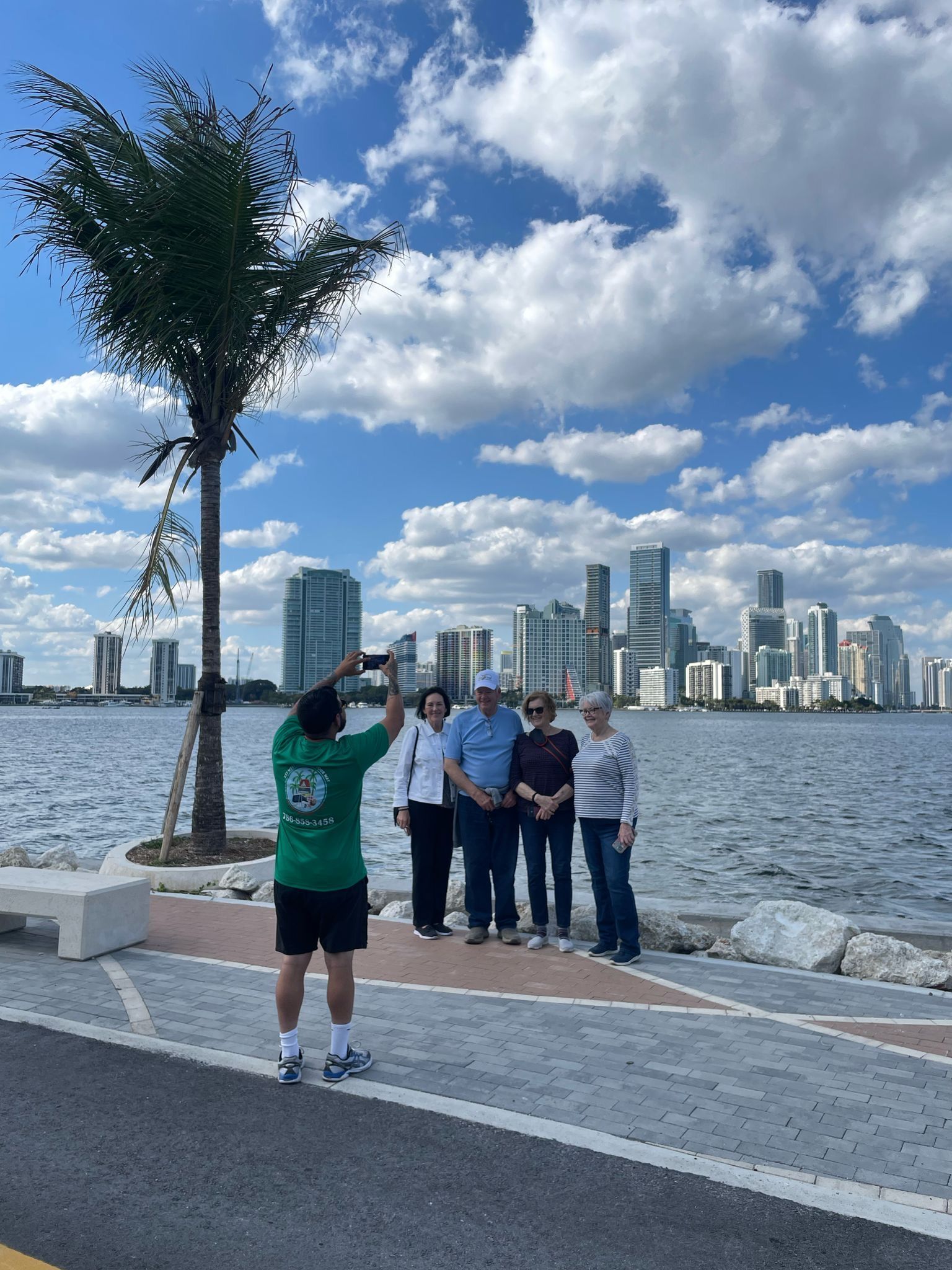 Tour guide taking a group photo with Miami skyline in the background during a city sightseeing tour
