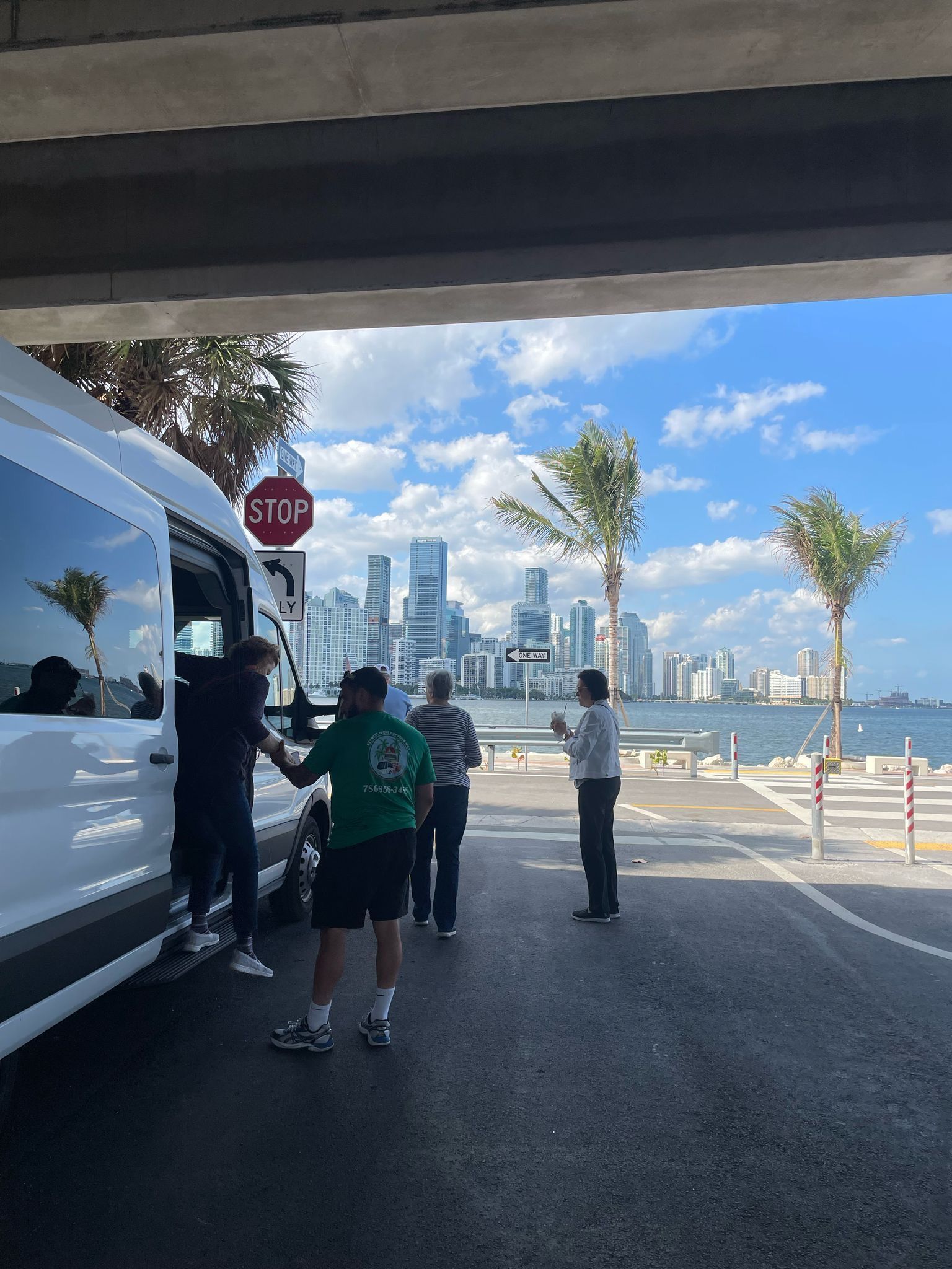 Miami Top City Tours guests boarding the van at a scenic stop with the downtown Miami skyline in the background
