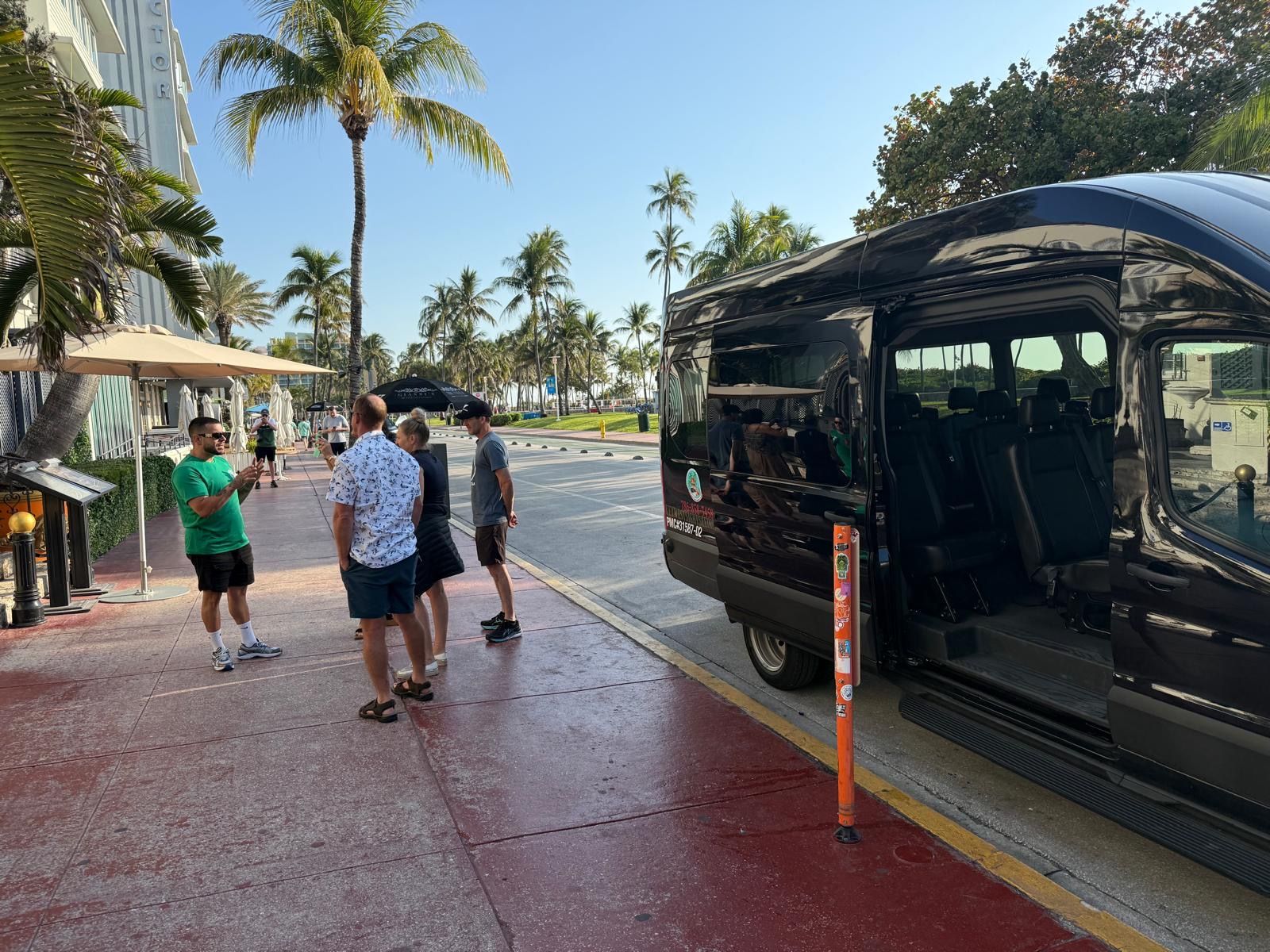 Alex the Miami super tour guide in Ocean Drive talking to passengers with the Miami Black tour bus parked. 