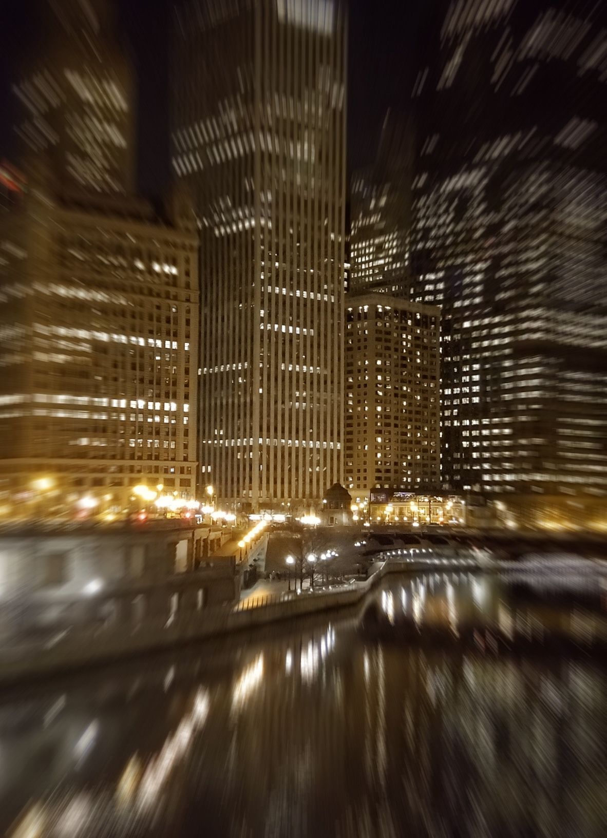 City skyscrapers at night, lights reflecting on a river, blurred motion effect.