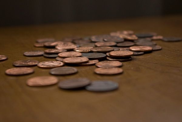 Pile of copper pennies scattered on a wooden surface.