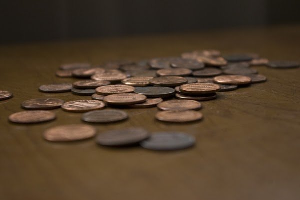 A pile of coins laying on a wooden table.