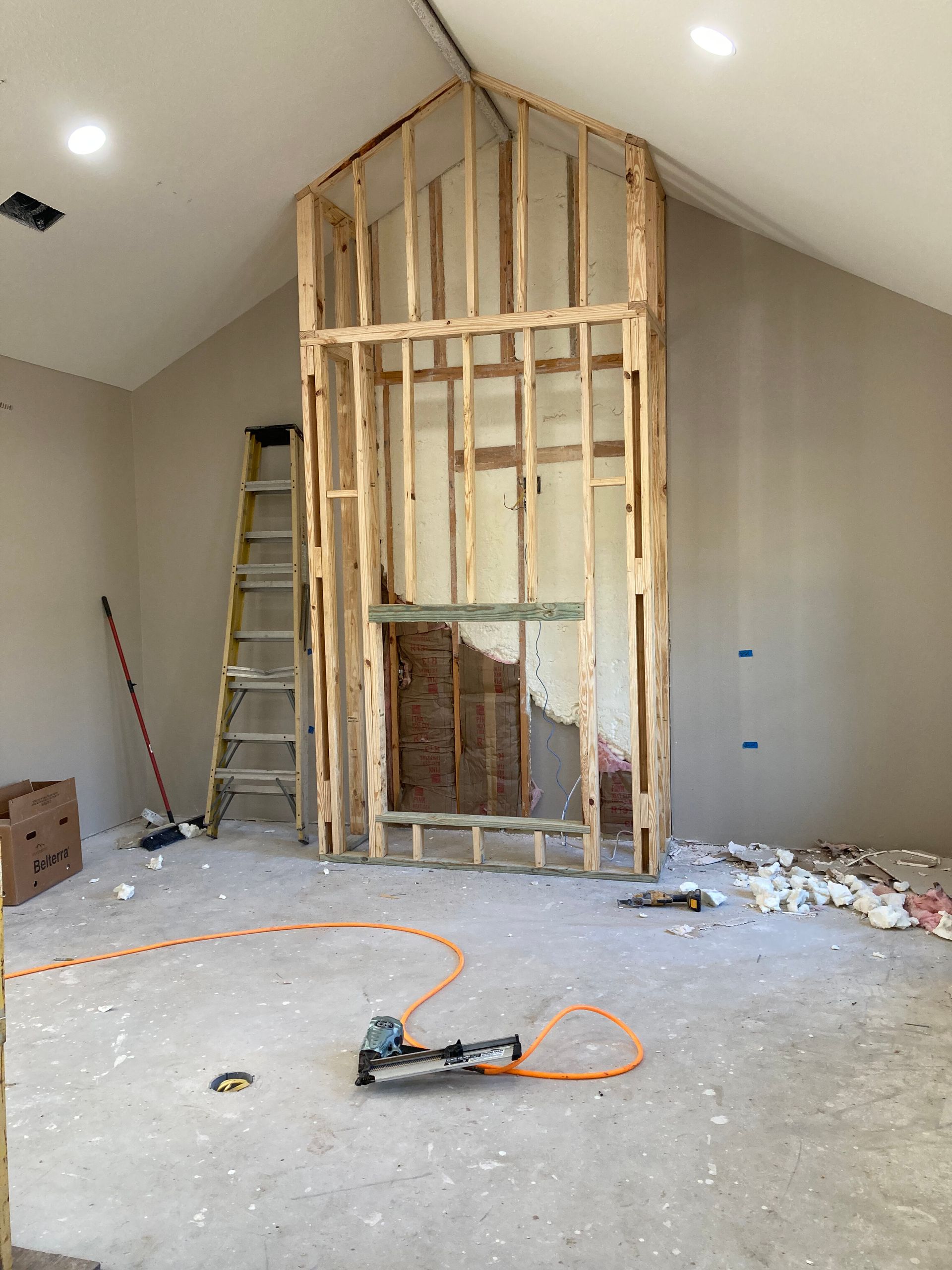 Renovation room with exposed wall framing, ladder, and power tools on the floor
