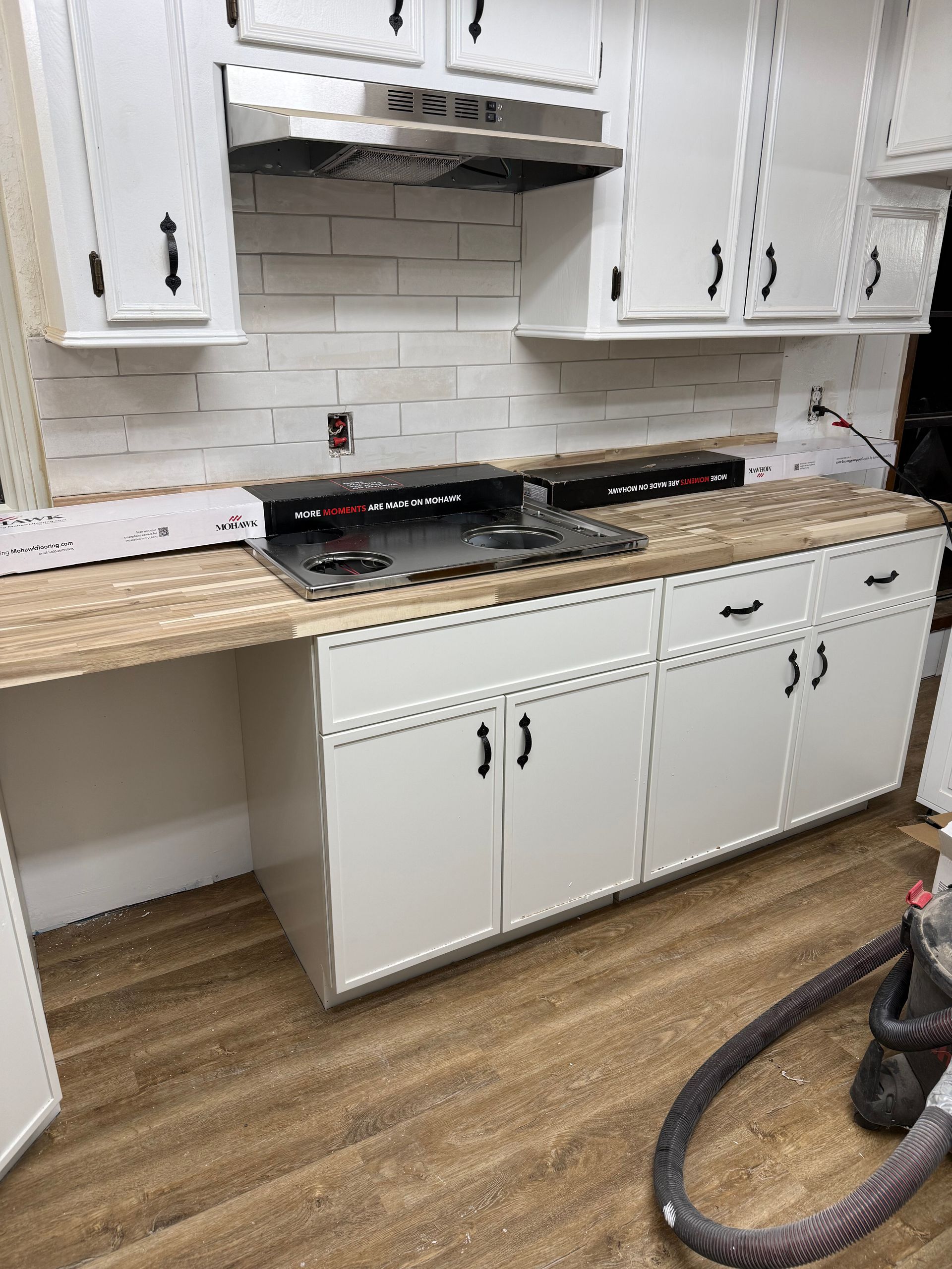 White kitchen with granite counters, black range, white cabinets, and a vacuum on the floor.