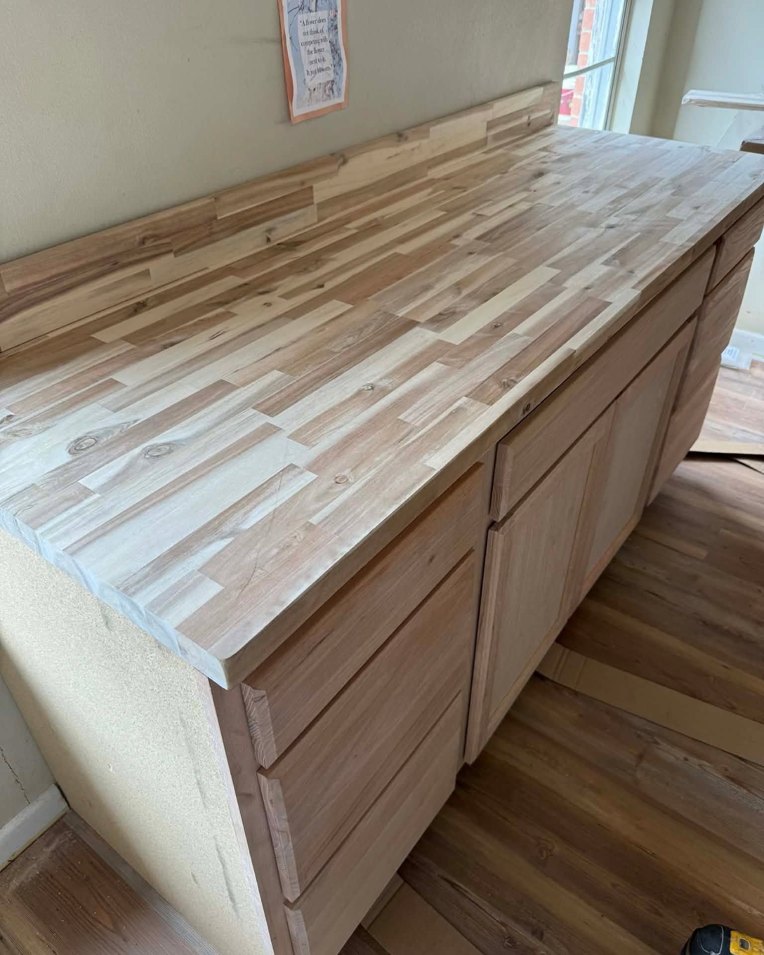 Wooden butcher-block countertop on light wood cabinets in a kitchen corner