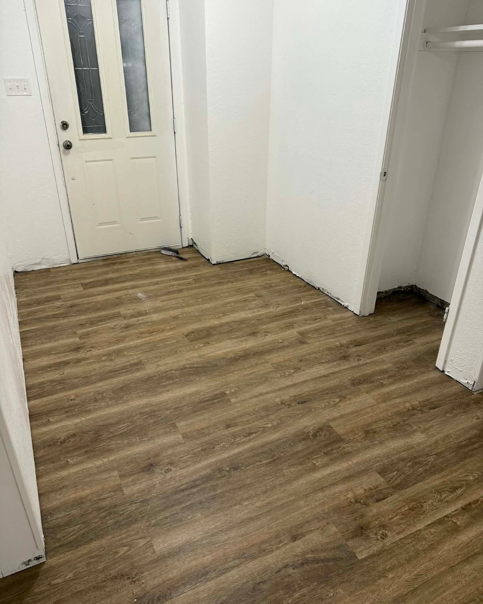 Empty room with wood-look flooring and white walls, viewed toward a doorway.