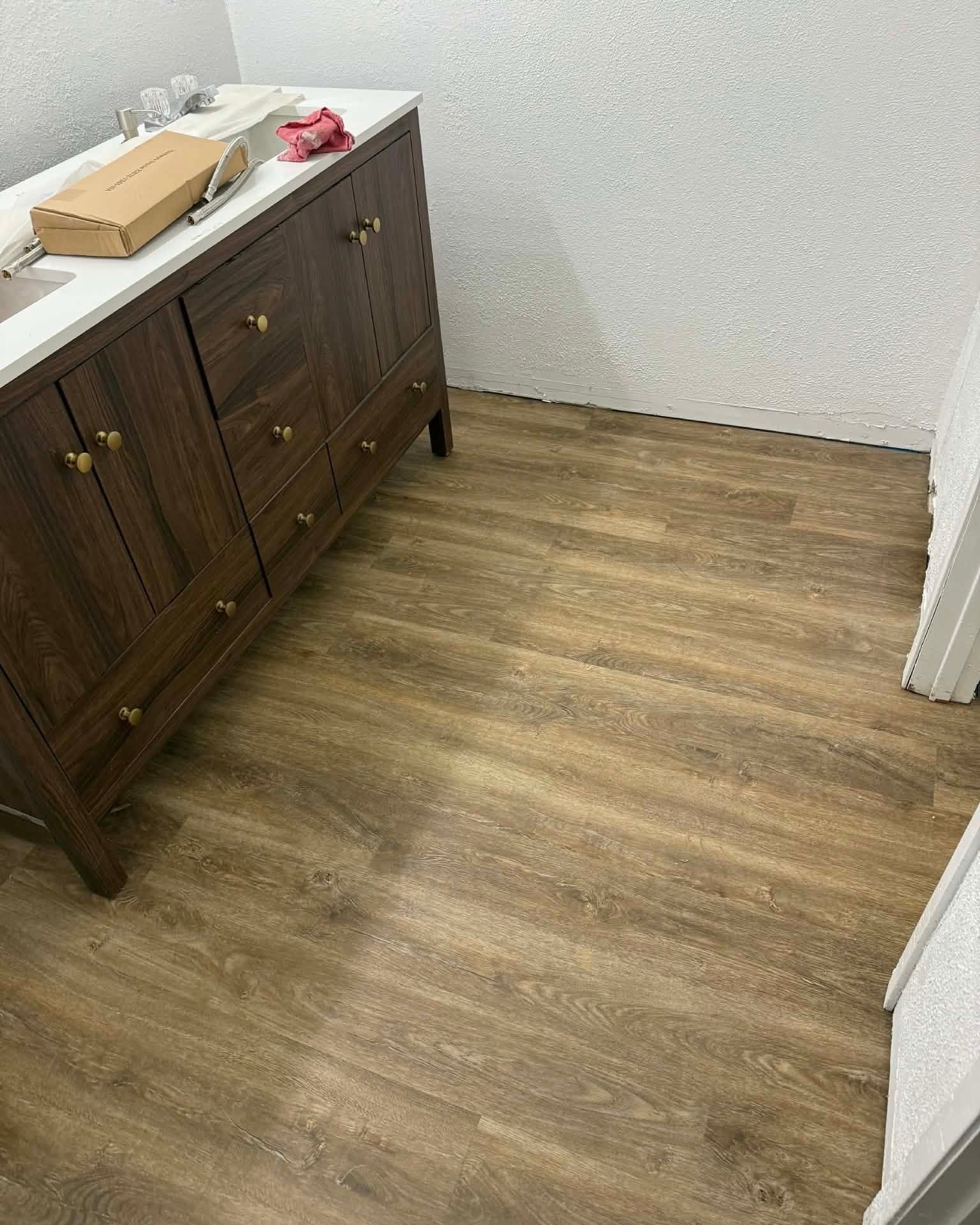 Small room with wood-look flooring and a dark cabinet against a white wall.