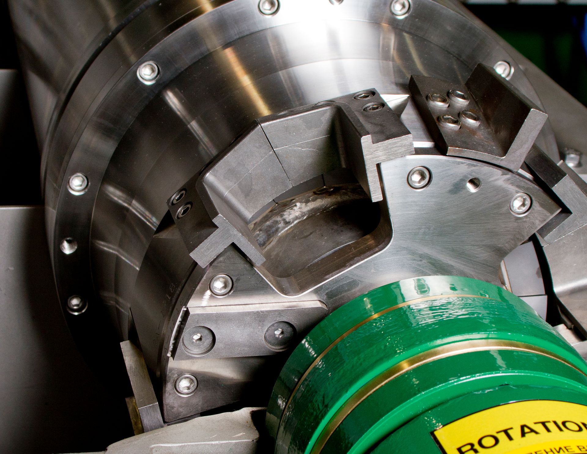 Close-up of a metallic industrial machine with bolts and a green rotating component