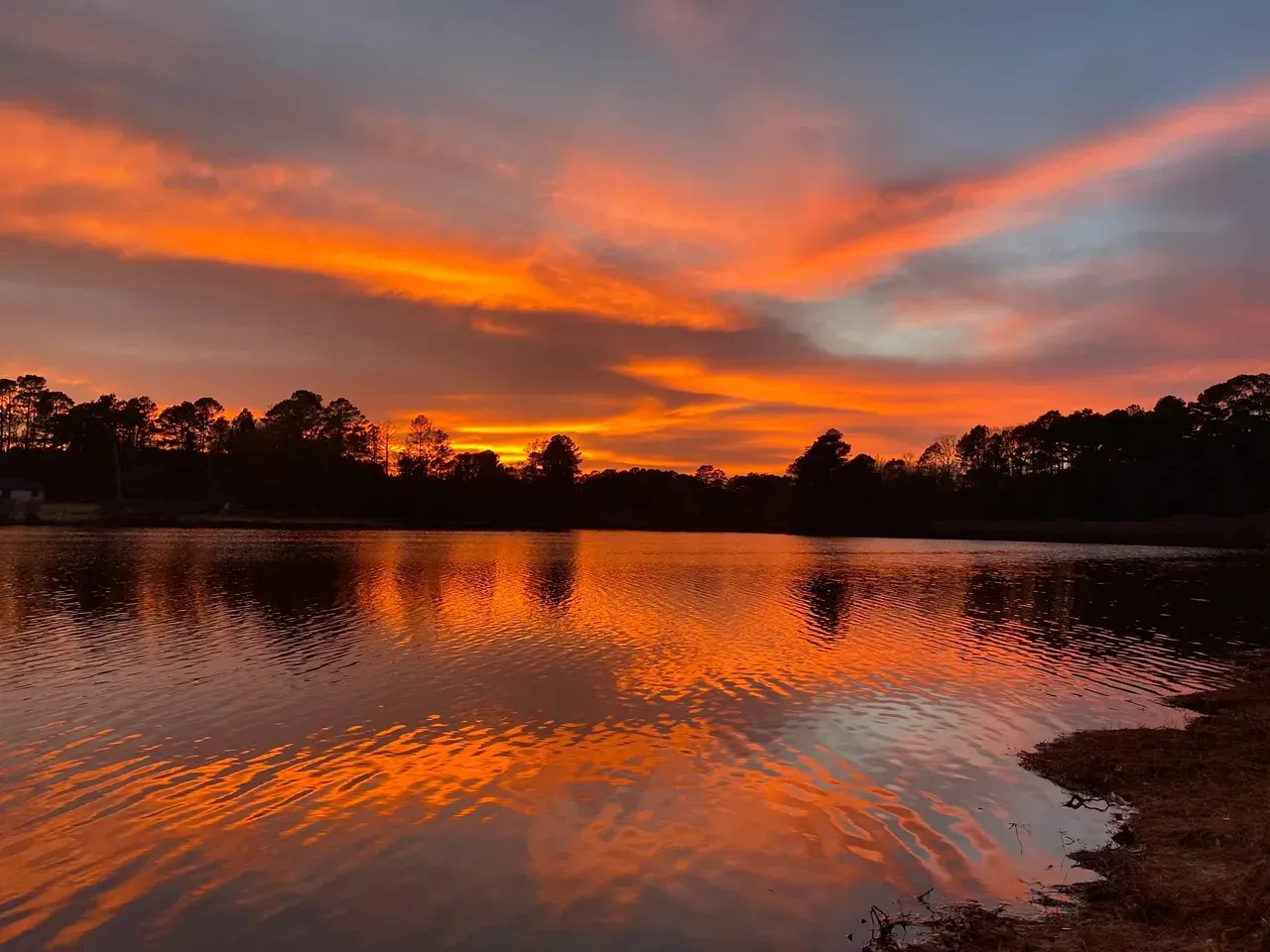 A sunset over a lake with trees in the background