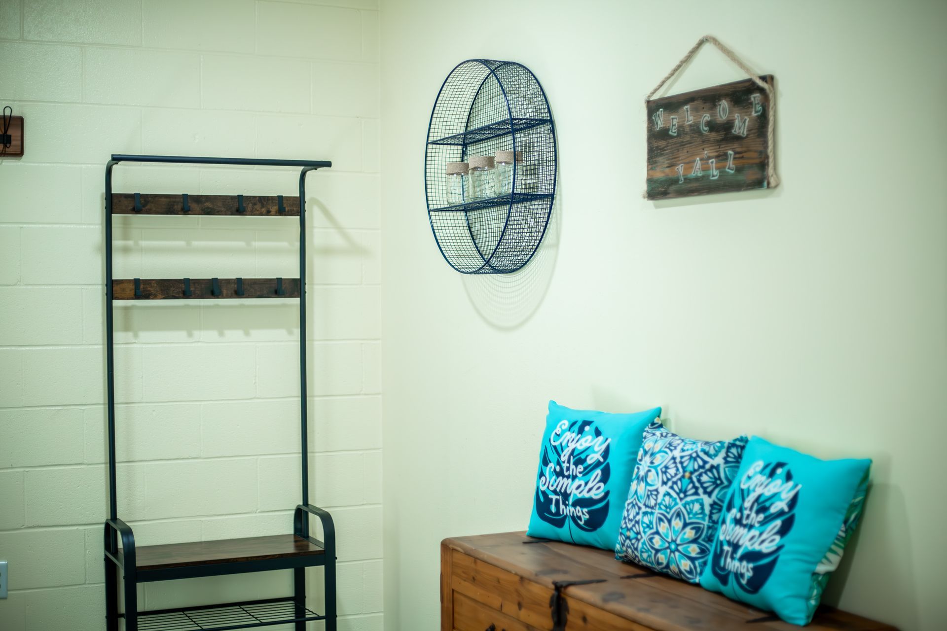 A living room with a couch , a shelf , and a sign on the wall.