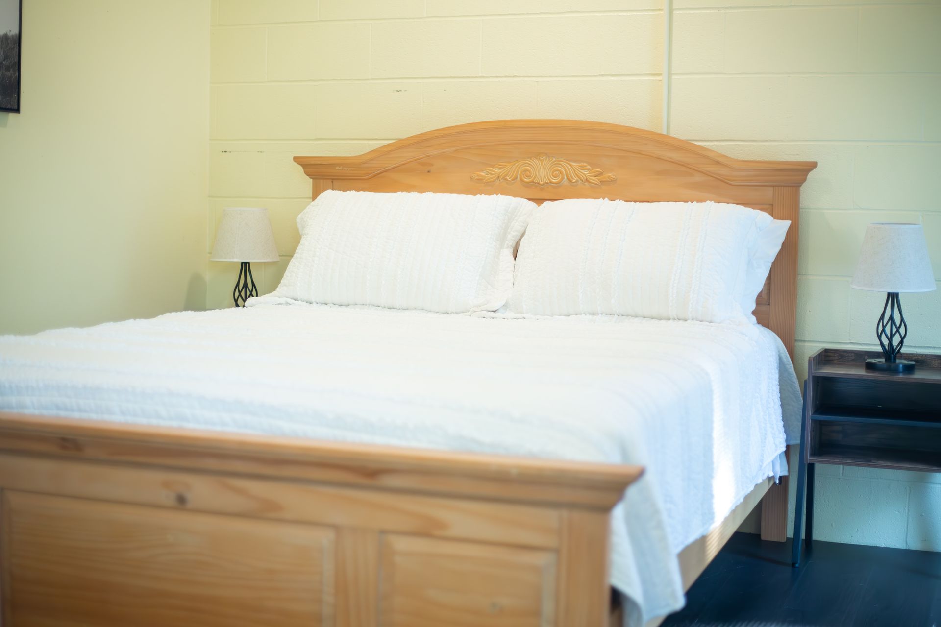 There is a bed with white sheets and pillows in the room.