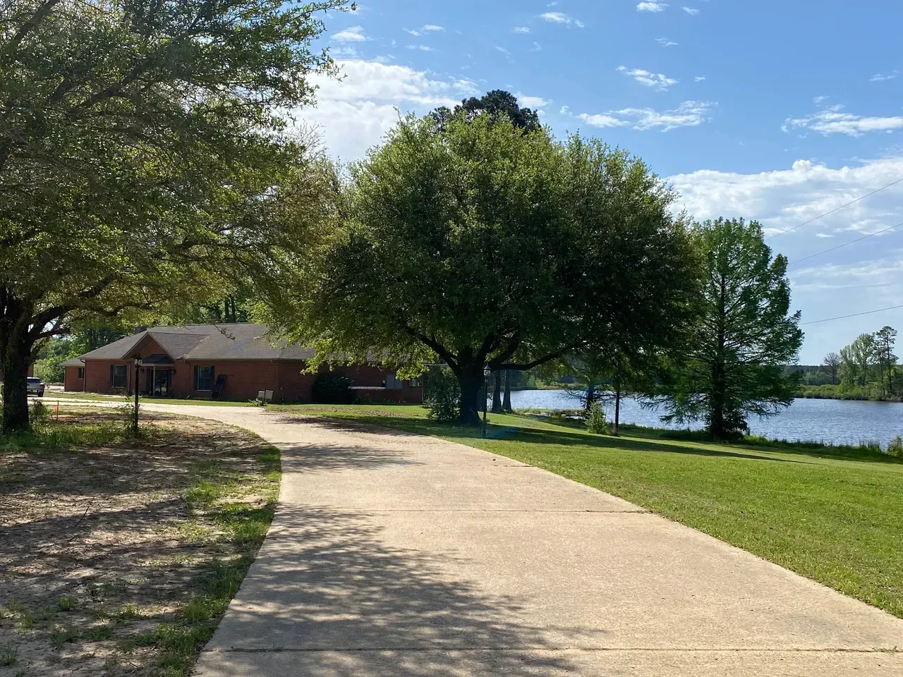 A driveway leading to a house with a lake in the background.