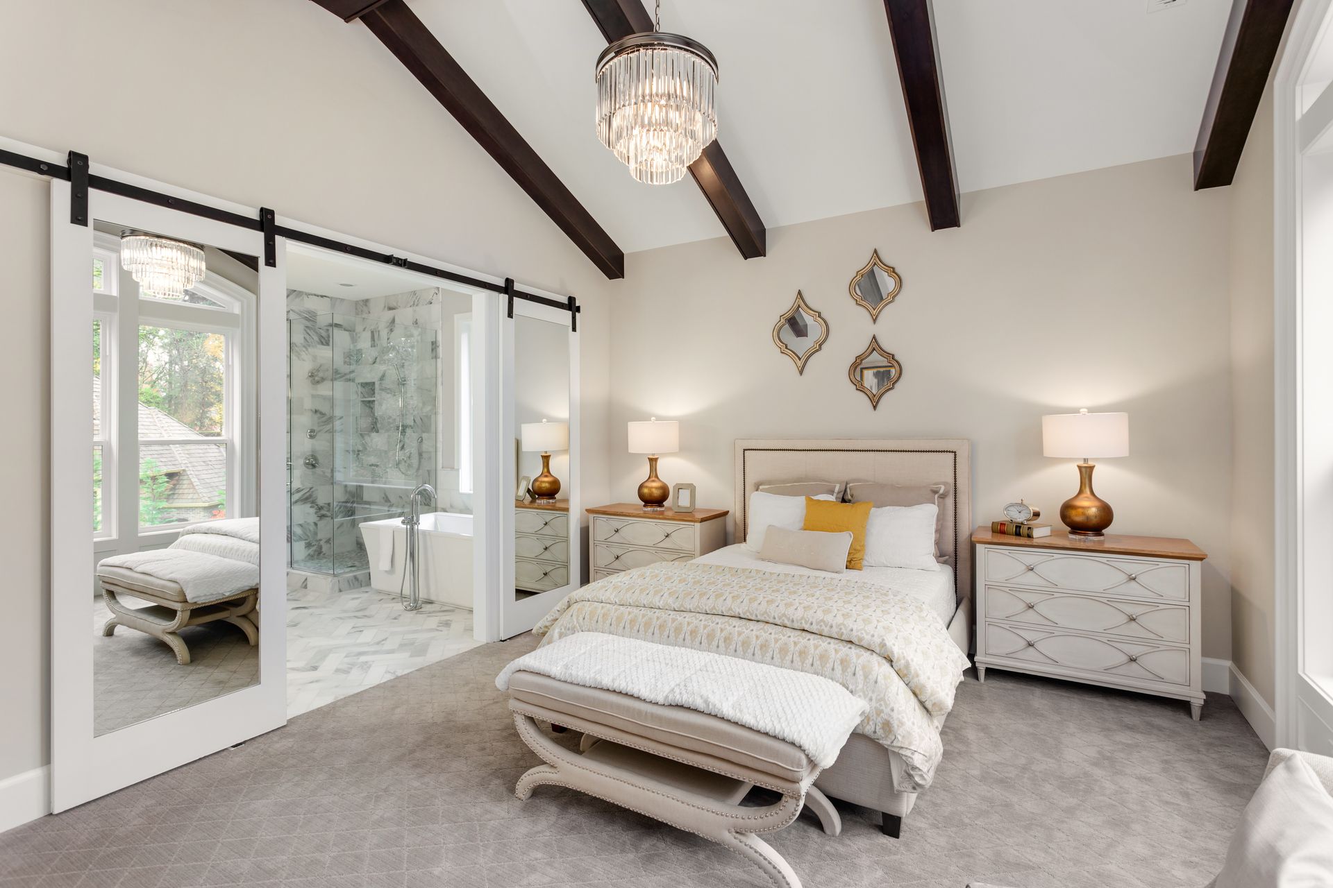 A bedroom with a bed , dresser , nightstand , mirror and sliding barn doors.