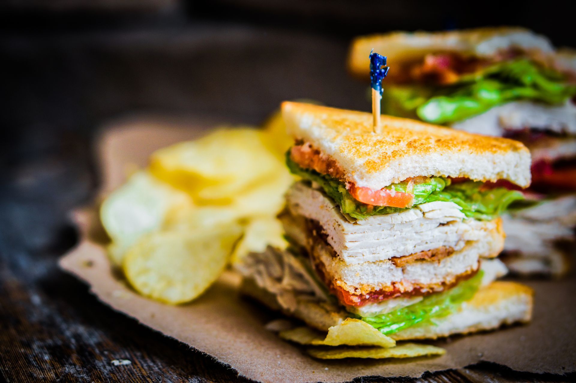 A club sandwich with potato chips on a wooden table.