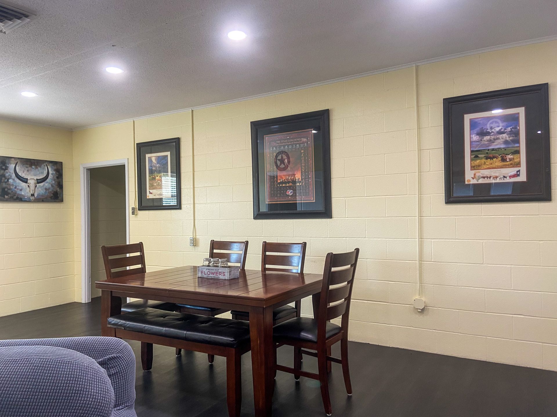 A dining room with a table and chairs and paintings on the walls.