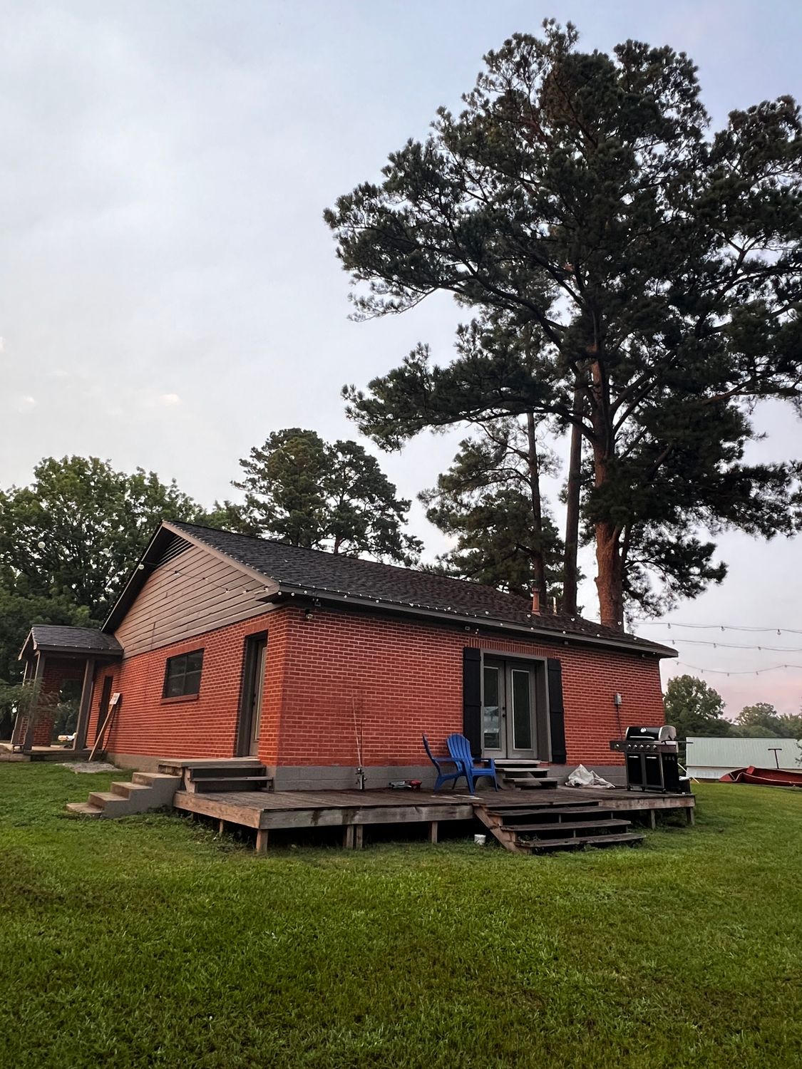 A brick house with a deck and trees in the background
