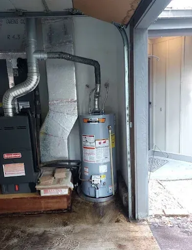 Basement utility area with furnace, water heater, and exposed ductwork beside a doorway