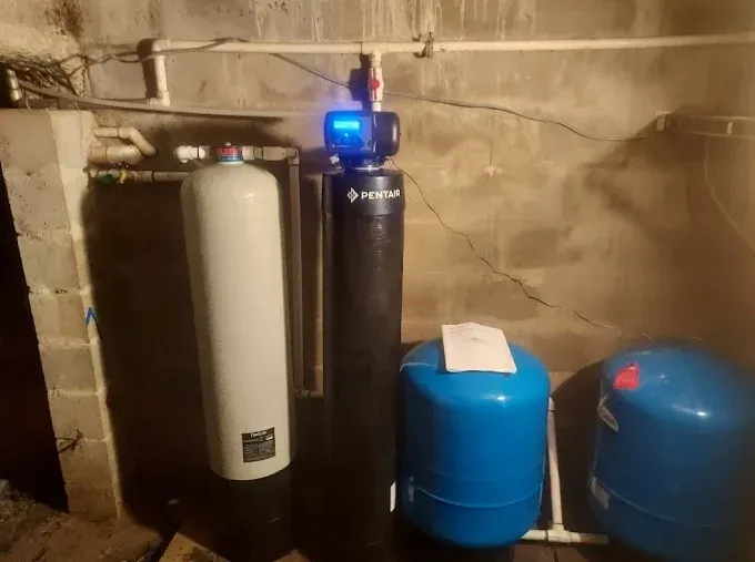 Water softener and pressure tanks installed in a basement utility room.