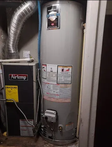 Basement HVAC equipment: a gray water heater beside a black furnace with ductwork.