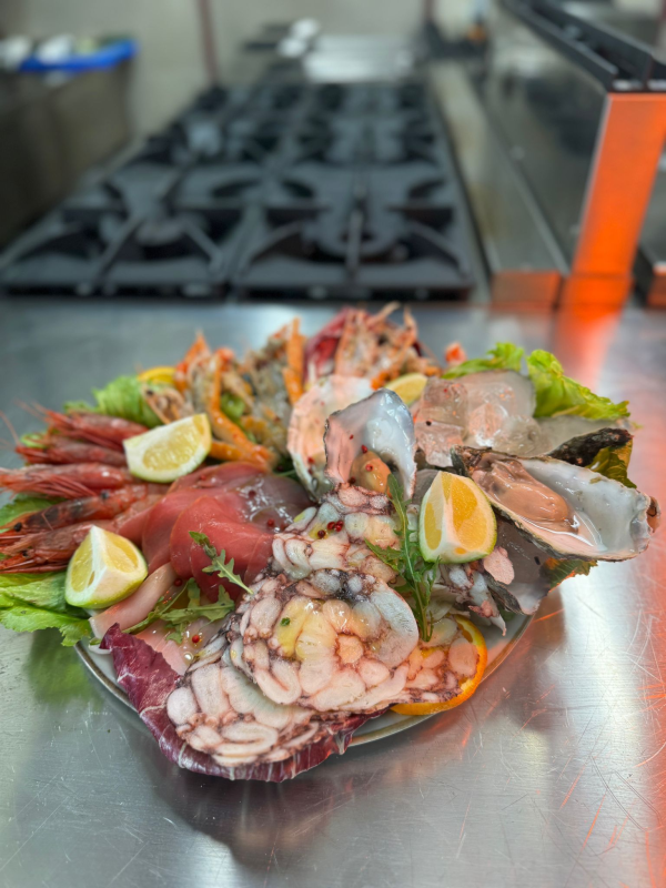 Piatto di frutti di mare con gamberi, polpo e fette di limone su un vassoio d'argento in cucina.