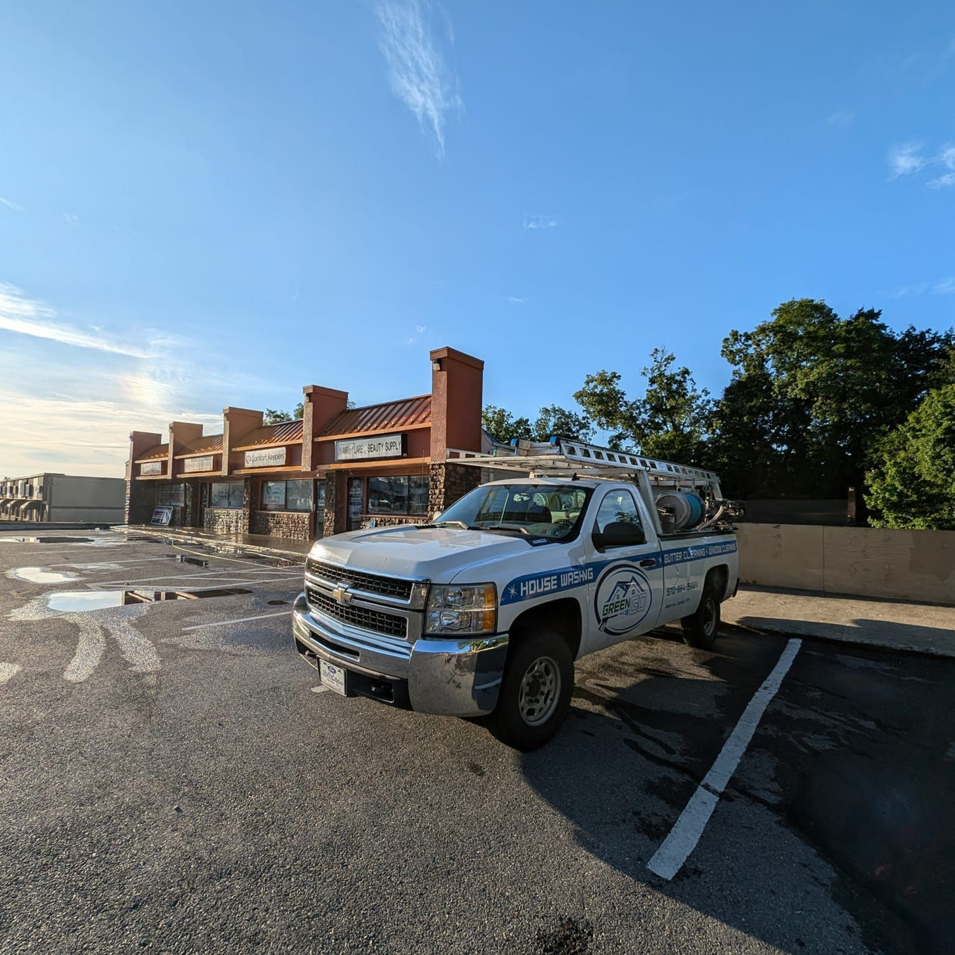 White work truck parked in front of a commercial building on a sunny day.