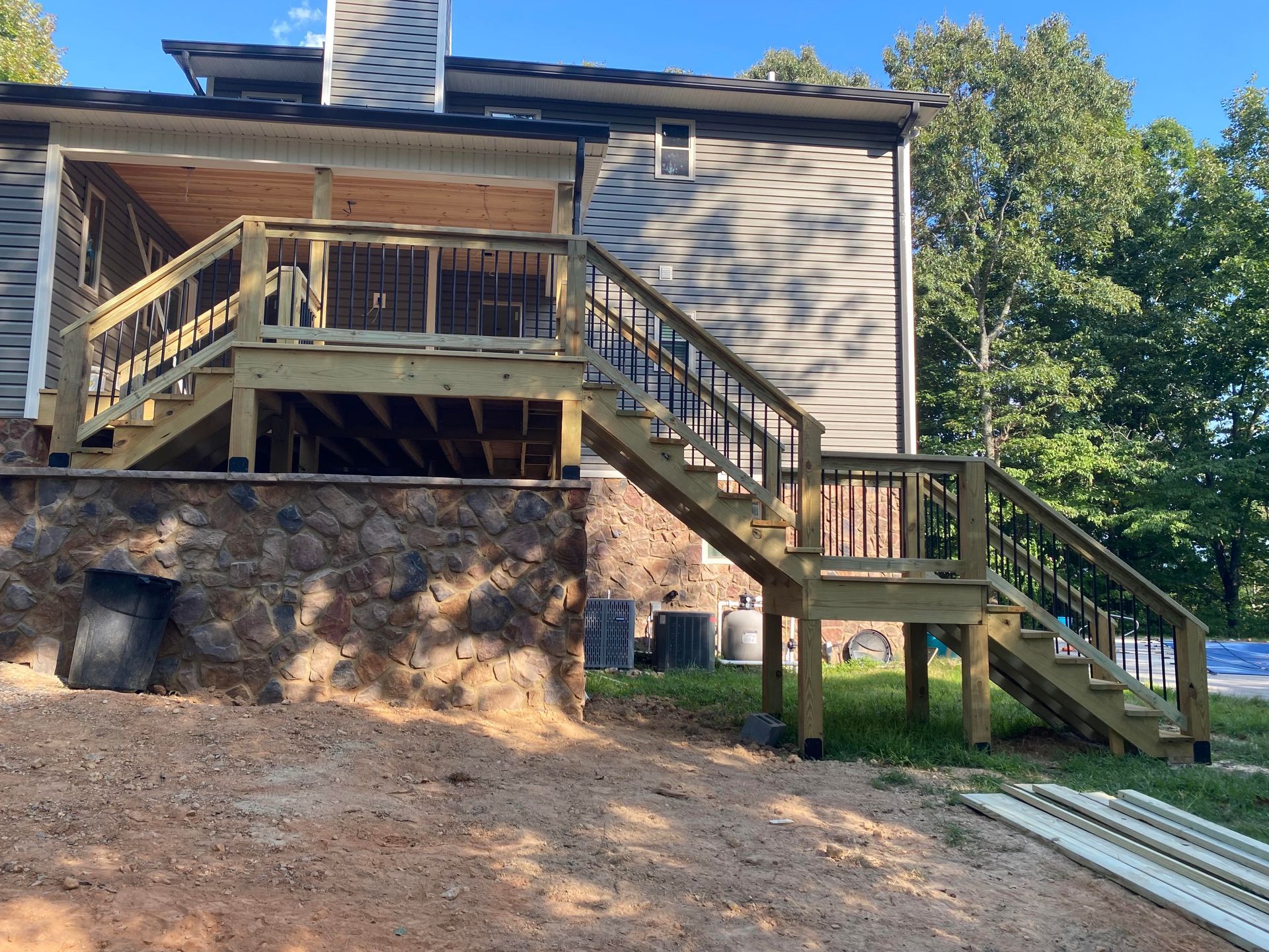 House deck with stairs and a stone retaining wall on a wooded hillside