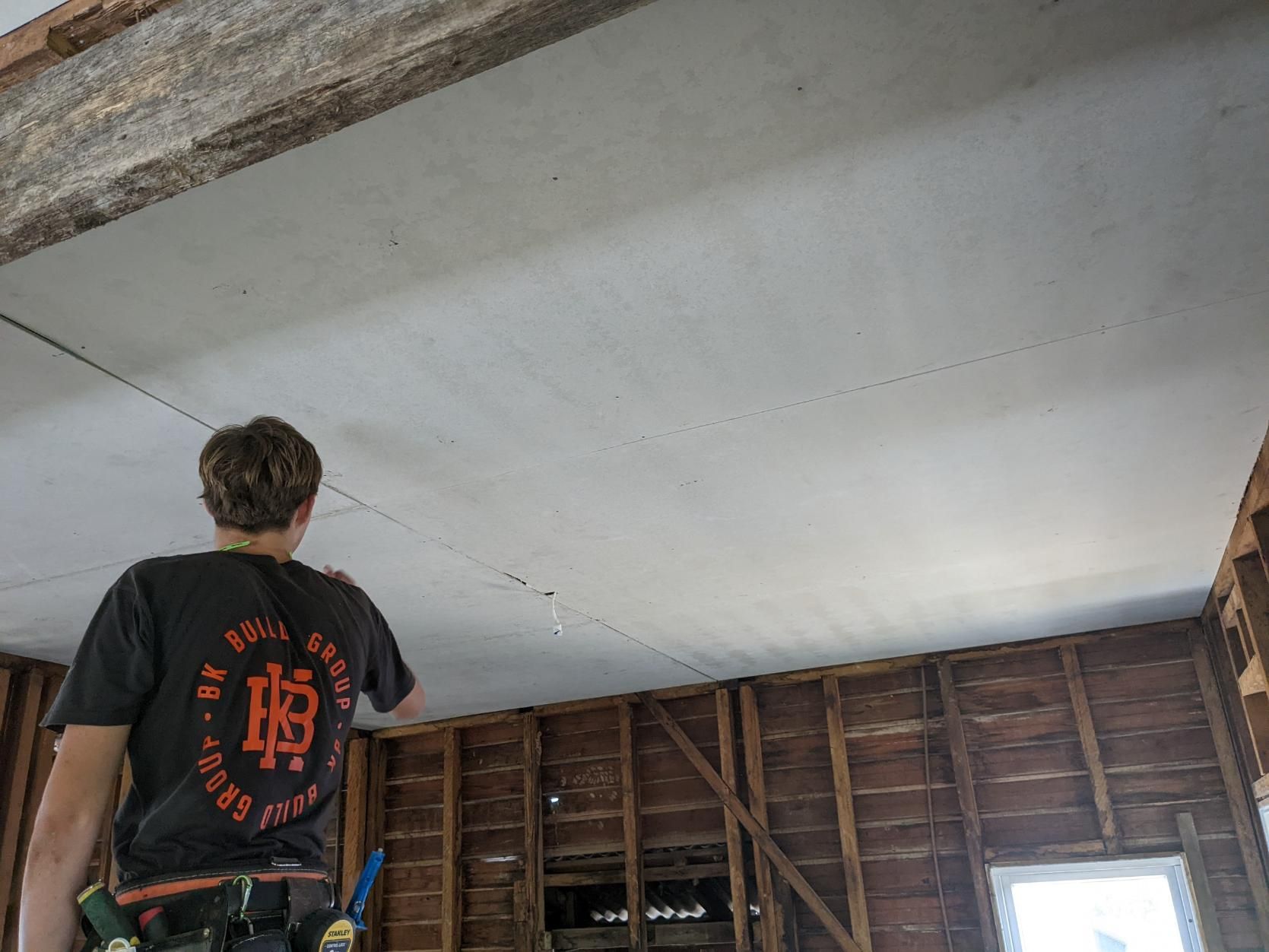 A Man is Standing in a Room Looking Up at the Ceiling — BK Build Group in Sawtell, NSW