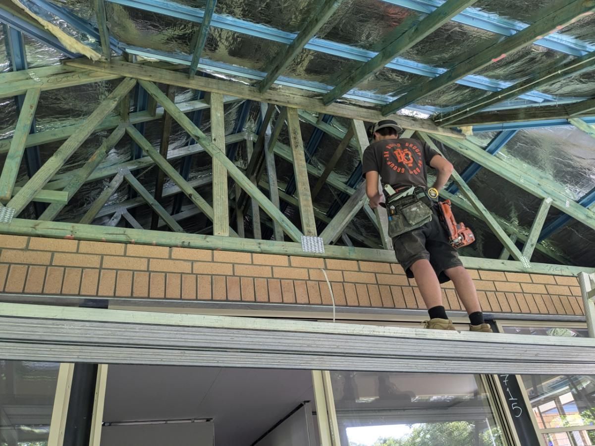 A Man is Standing on a Ladder Under a Roof — BK Build Group in Nambucca Heads, NSW