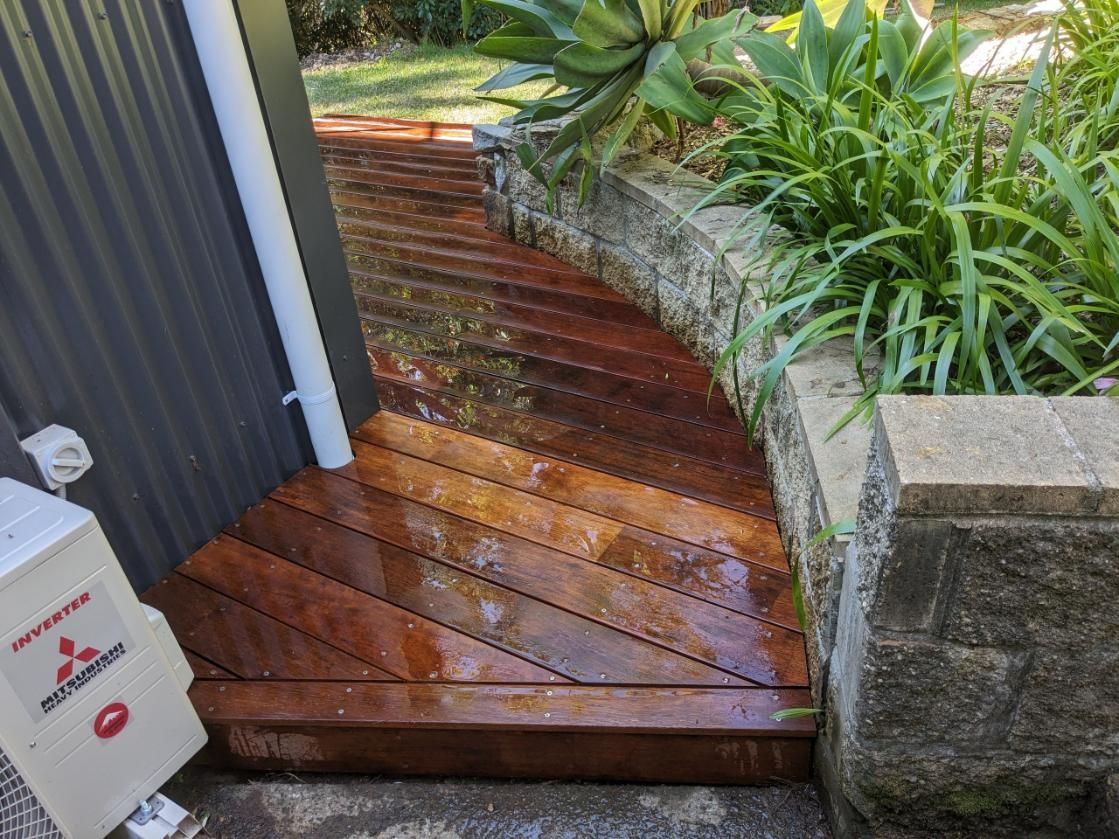 A Wooden Walkway Leading to a House Next to a Brick Wall — BK Build Group in Bellingen, NSW