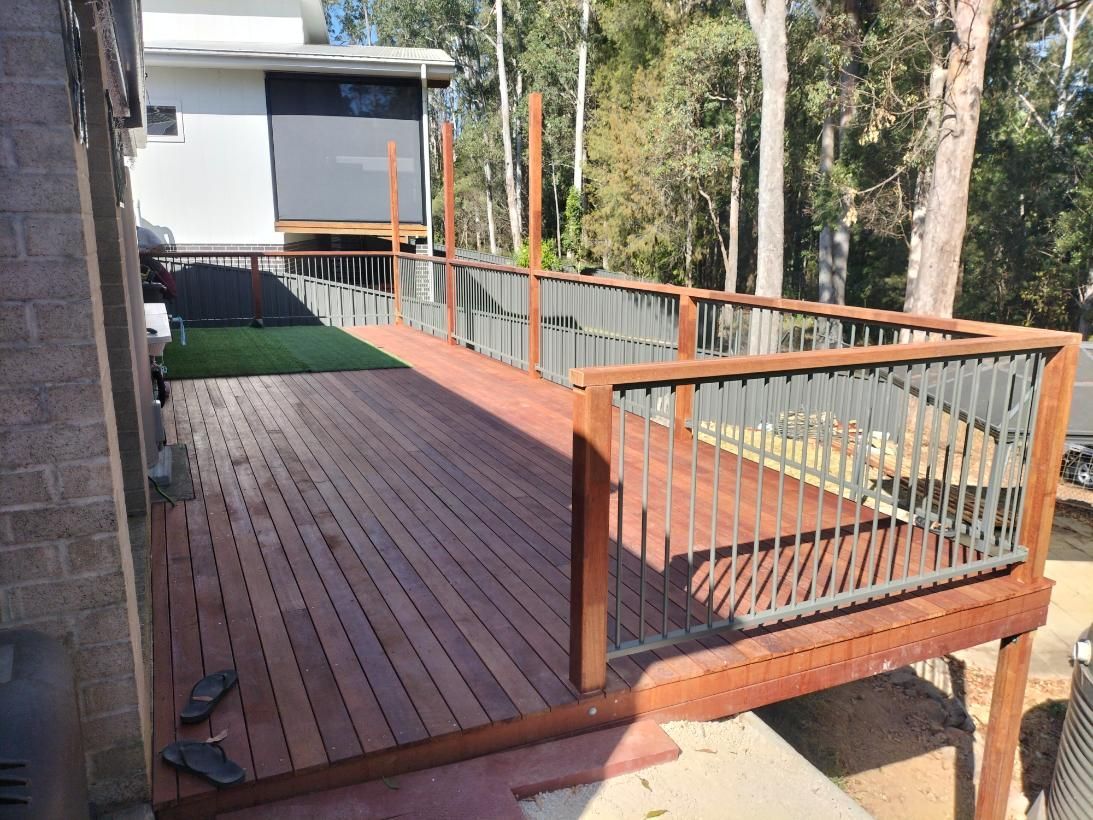A Wooden Deck With a Metal Railing is Being Built in Front of a House — BK Build Group in Sawtell, NSW