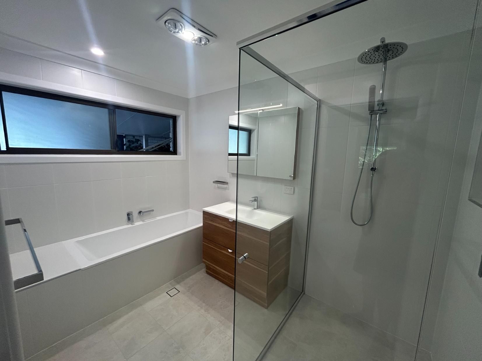 A Bathroom With a Bathtub , Sink , Shower and Mirror — BK Build Group in Coffs Harbour, NSW