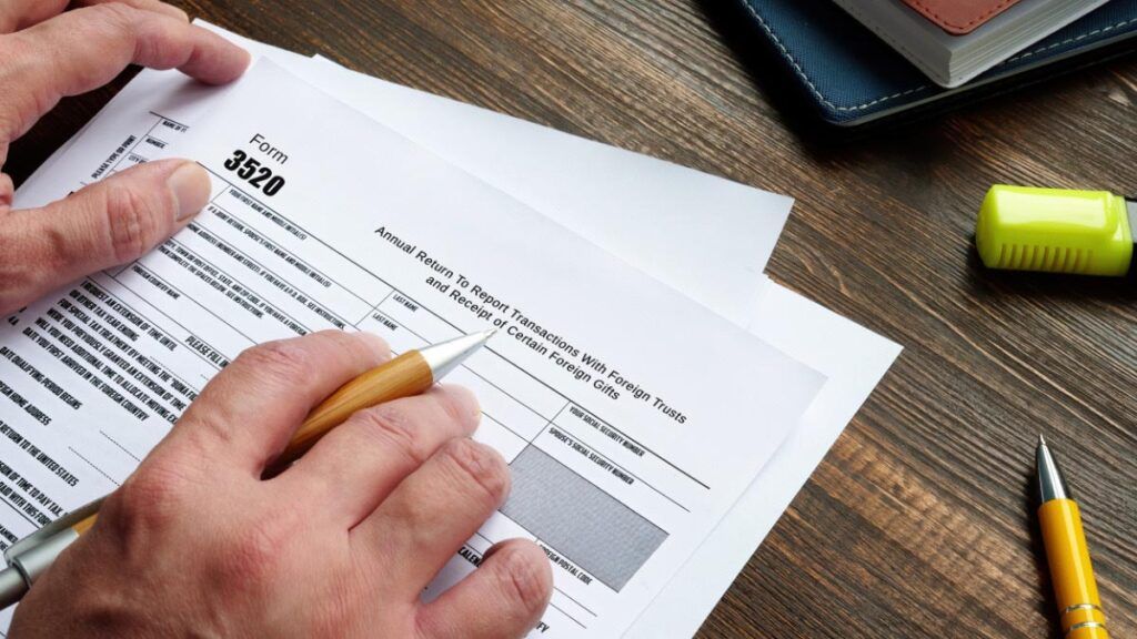 A person is filling out a tax form with a pen.