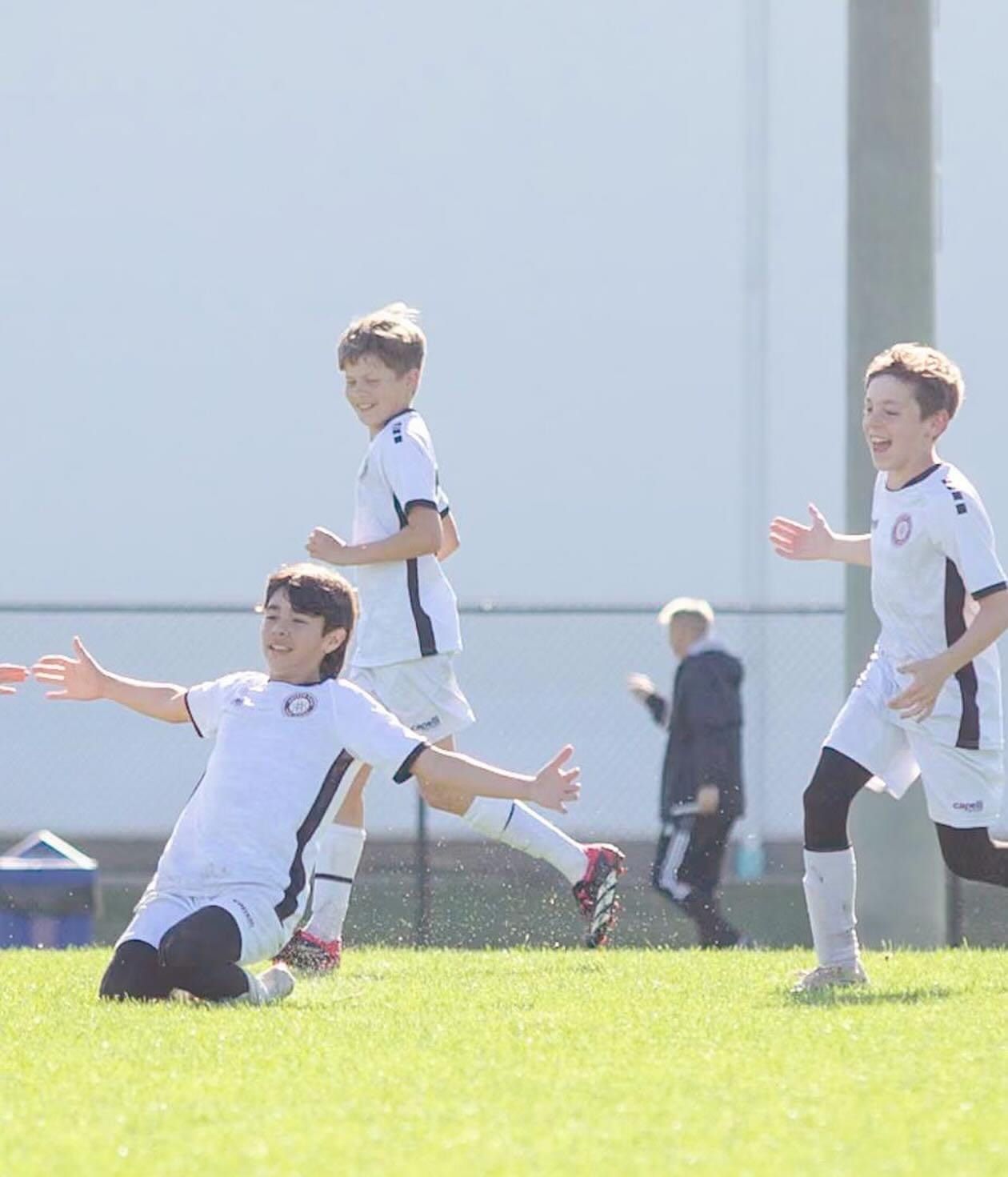 A group of young boys are playing soccer on a field.